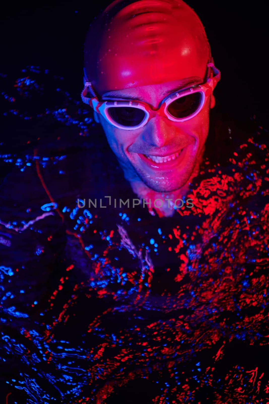 real triathlete swimmer having a break during hard training at lake on dark night neon gel color lights