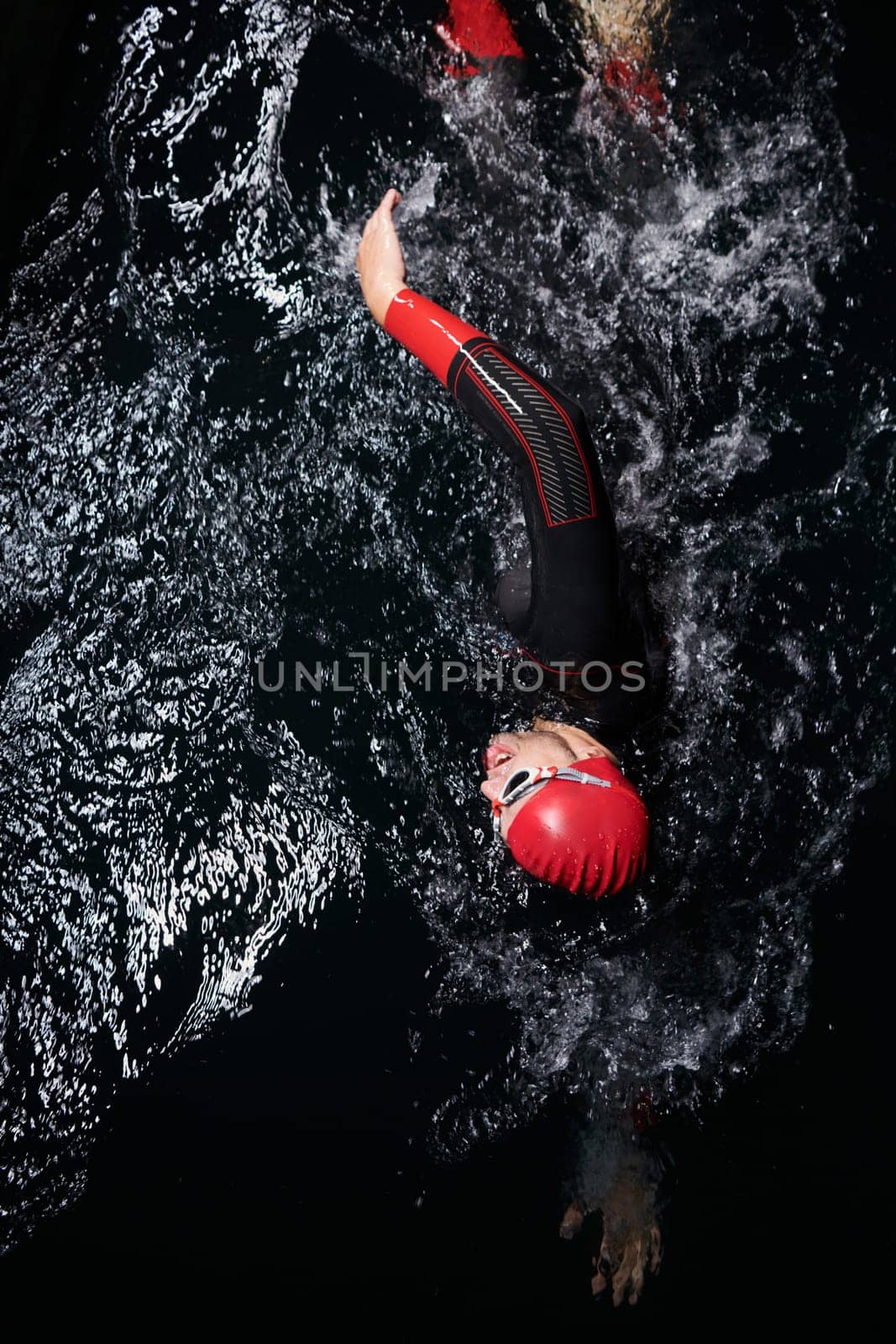 A determined professional triathlete undergoes rigorous night time training in cold waters, showcasing dedication and resilience in preparation for an upcoming triathlon swim competition by dotshock