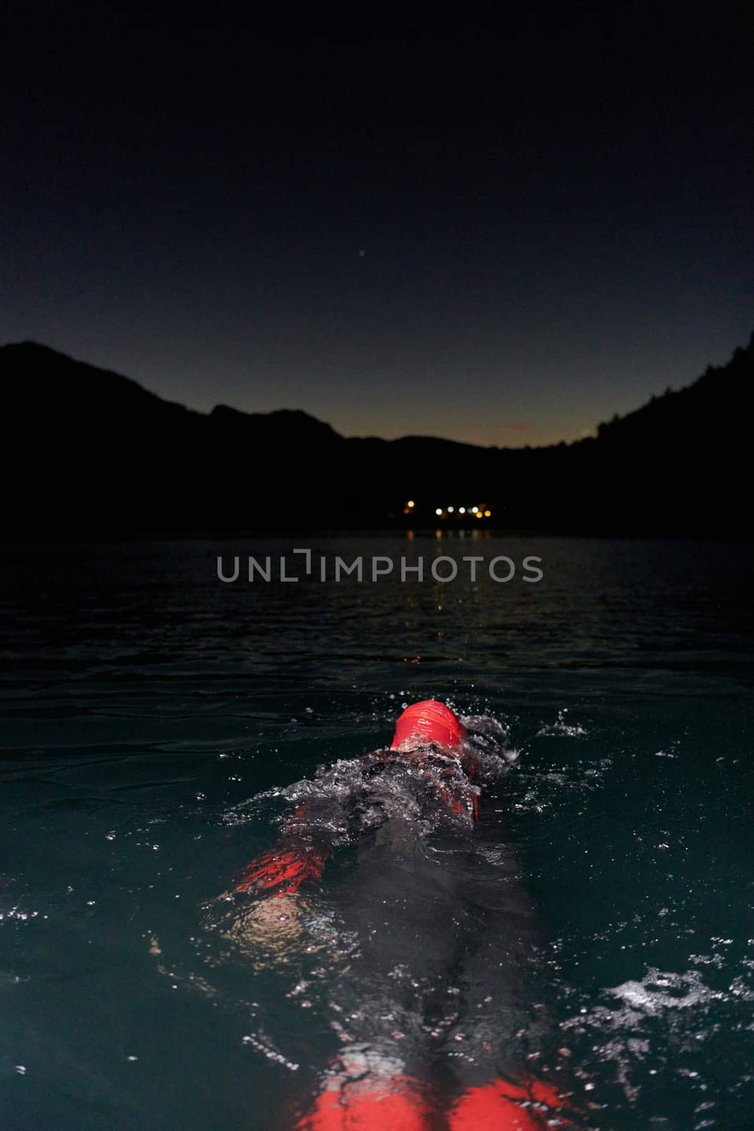 A determined professional triathlete undergoes rigorous night time training in cold waters, showcasing dedication and resilience in preparation for an upcoming triathlon swim competition.