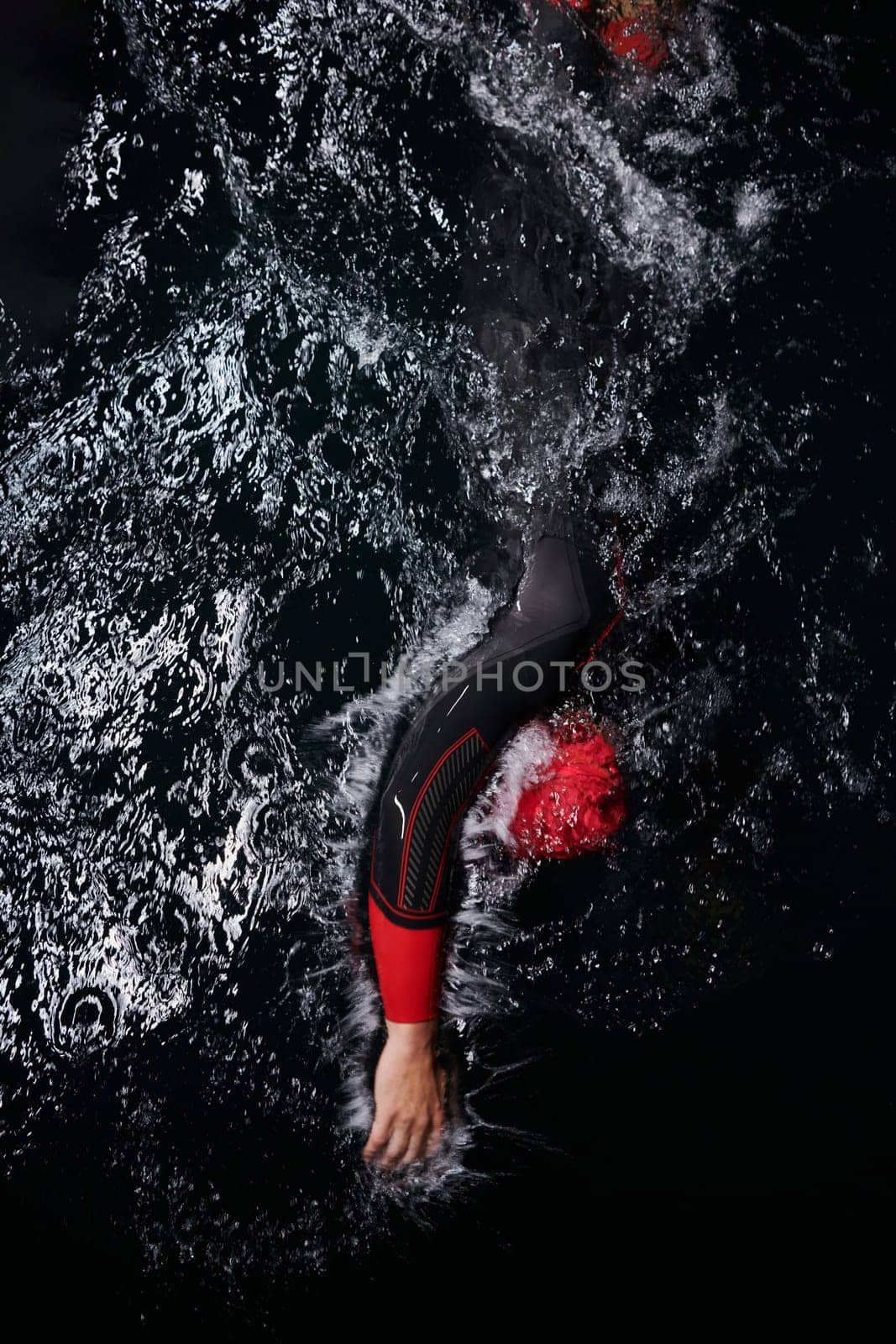 A determined professional triathlete undergoes rigorous night time training in cold waters, showcasing dedication and resilience in preparation for an upcoming triathlon swim competition by dotshock