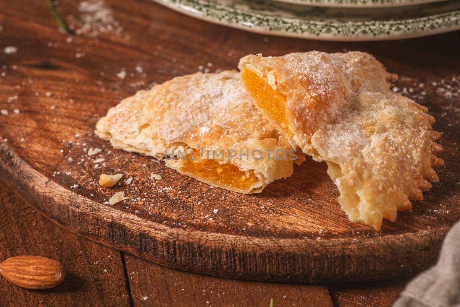 A crescent-shaped pastry whose filling is made of eggs and almonds wrapped in crispy dough, cut in an artisanal way and sprinkled with sugar.