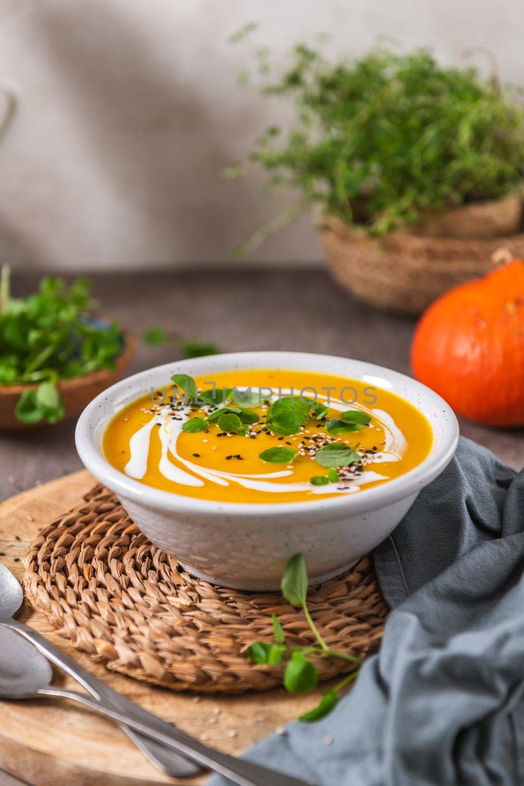 Delicious homemade creamy pumpkin soup with cream with sesame seeds and watercress.