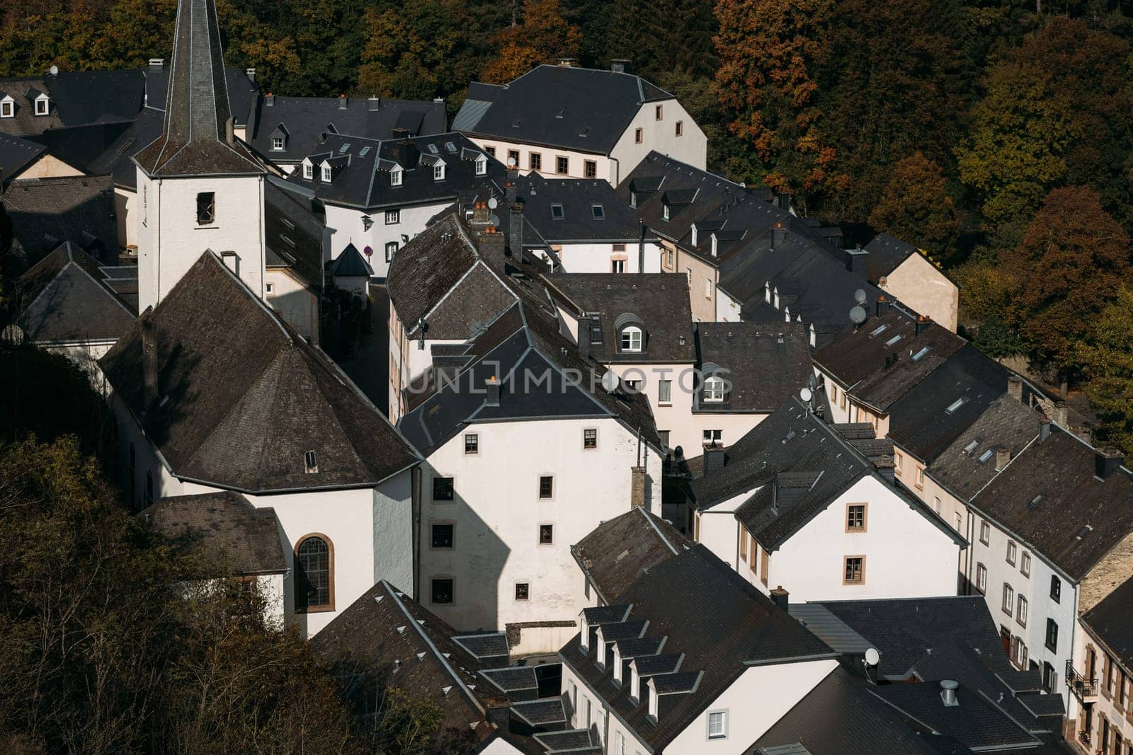 Ancient town in Luxemburg with identical houses with white facades and dark roofs. Small town with similar architecture located among forest