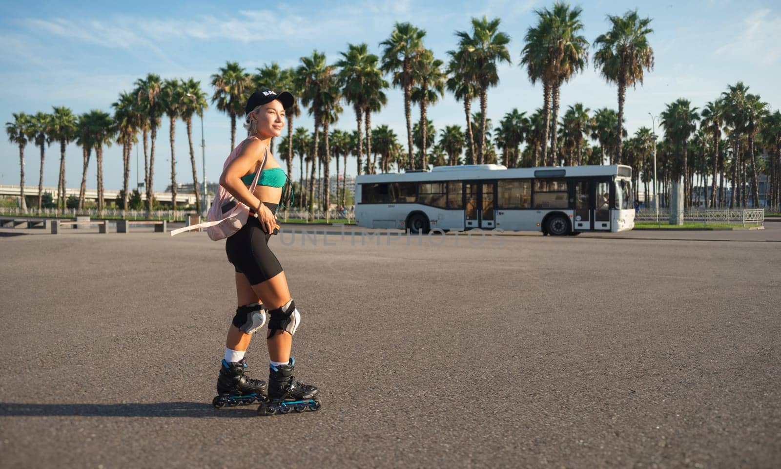 sporty girl on roller skates against the background of the city in the sunset light on a summer day