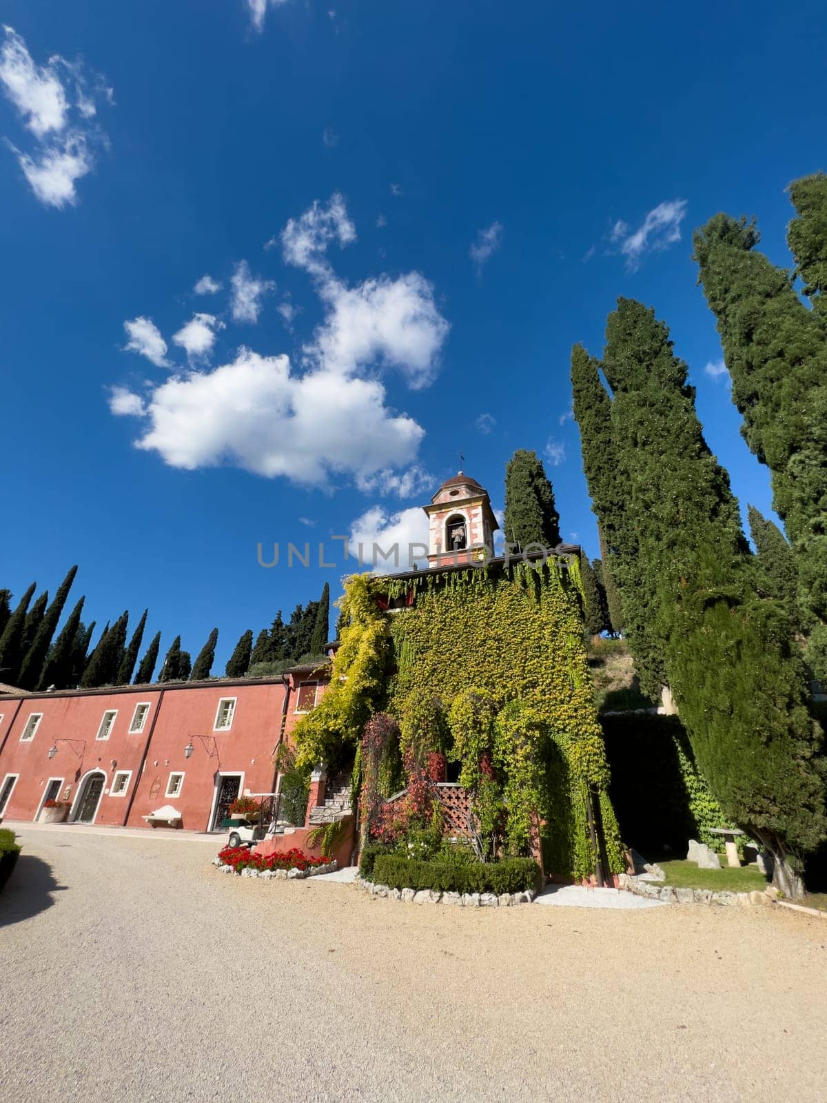 Red facade of the villa Cordevigo Wine Relais is covered with ivy. Italy by Nadtochiy