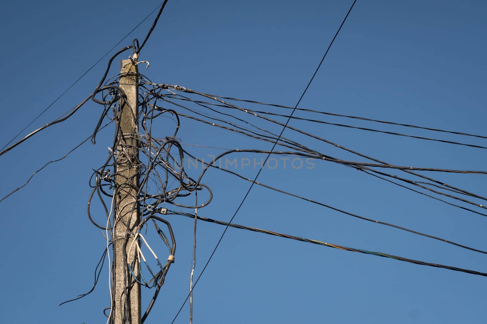 On the concrete pillar a large number of tangled wires. Old power lines. Electric wires. Flammable wiring