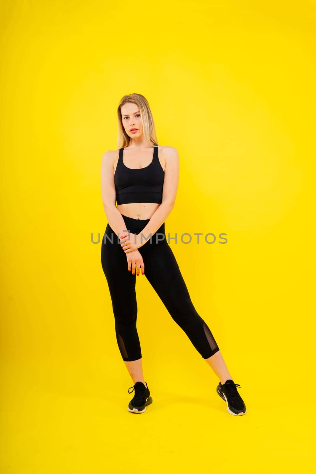 Beautiful young woman dressed in sports uniform, posing in studio on yellow red dark background.