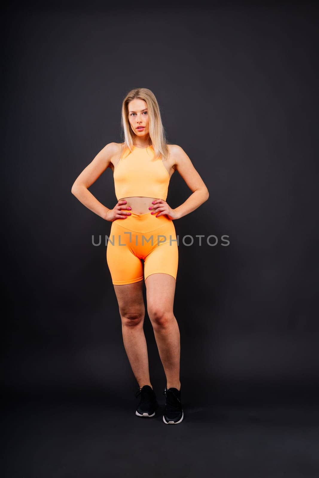 Beautiful young woman dressed in sports uniform, posing in studio on a yellow red dark background. by Zelenin