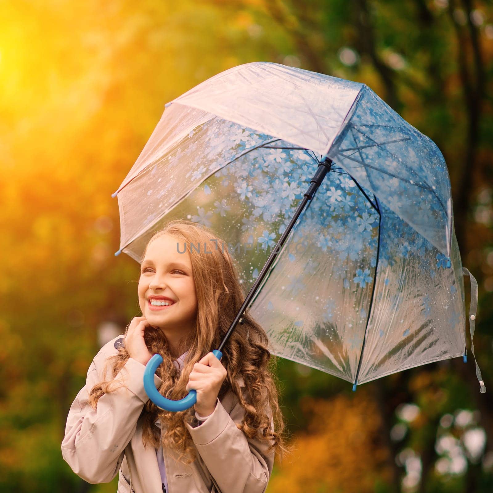 Young attractive smiling girl under umbrella in an autumn forest