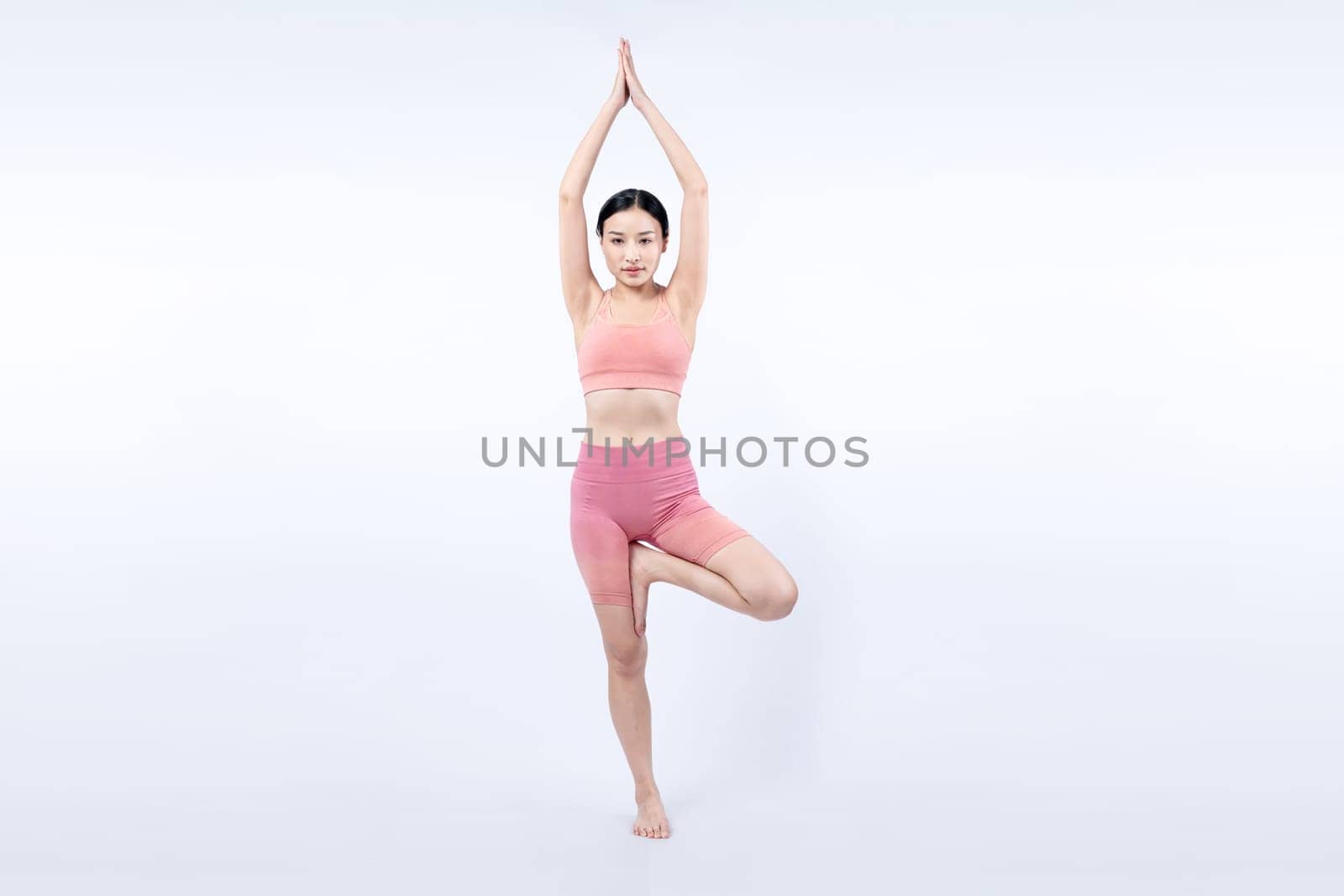 Asian woman in sportswear doing yoga exercise in standing pose on fitness as her workout training routine. Healthy body care and meditation yoga lifestyle in full shot on isolated background. Vigorous