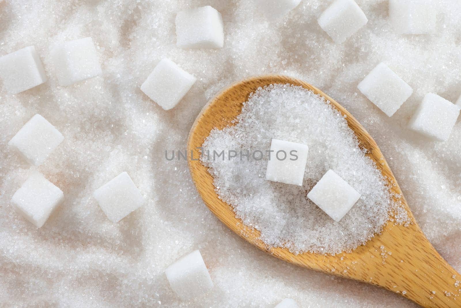 Wooden spoon full of refined granulated sugar. View from above.