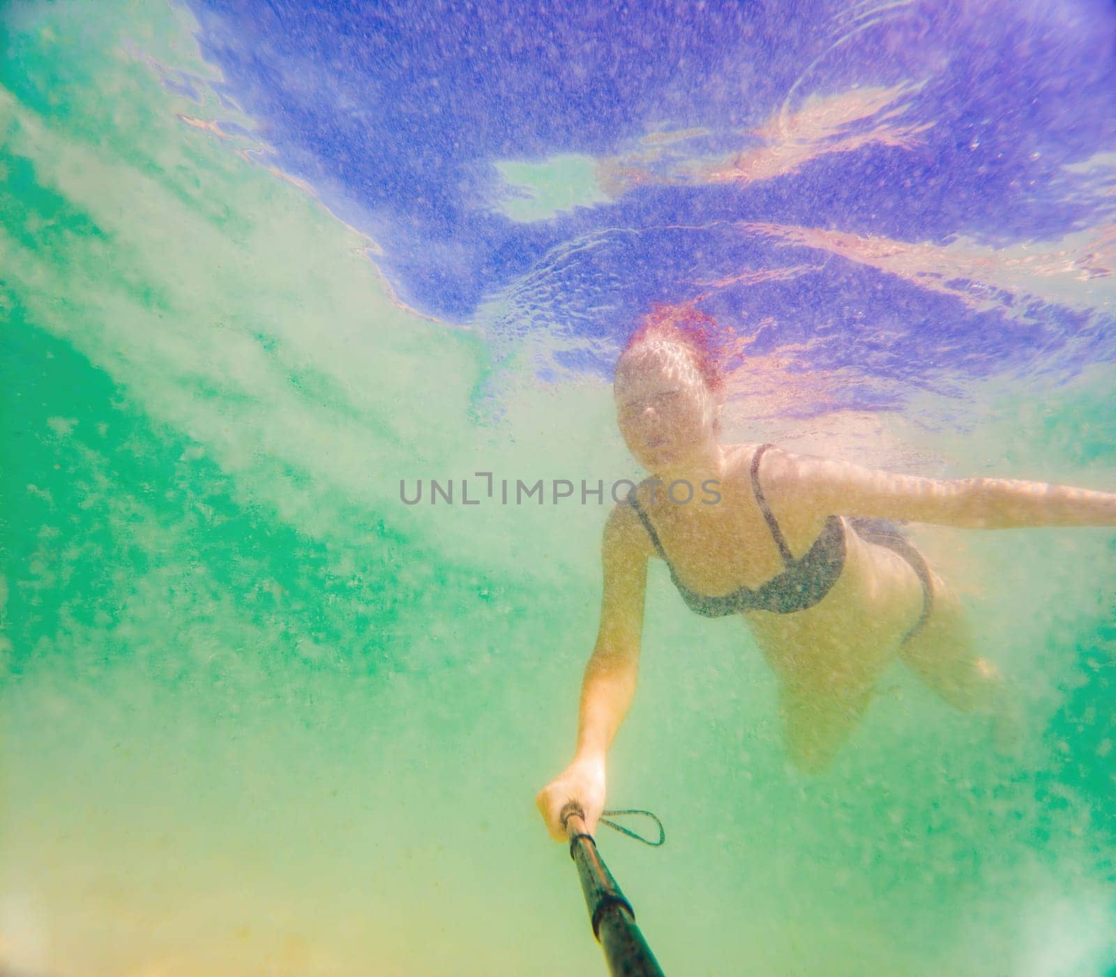 In an ethereal underwater scene, a pregnant woman gracefully floats, embodying the beauty of maternity beneath the tranquil surface of the sea by galitskaya