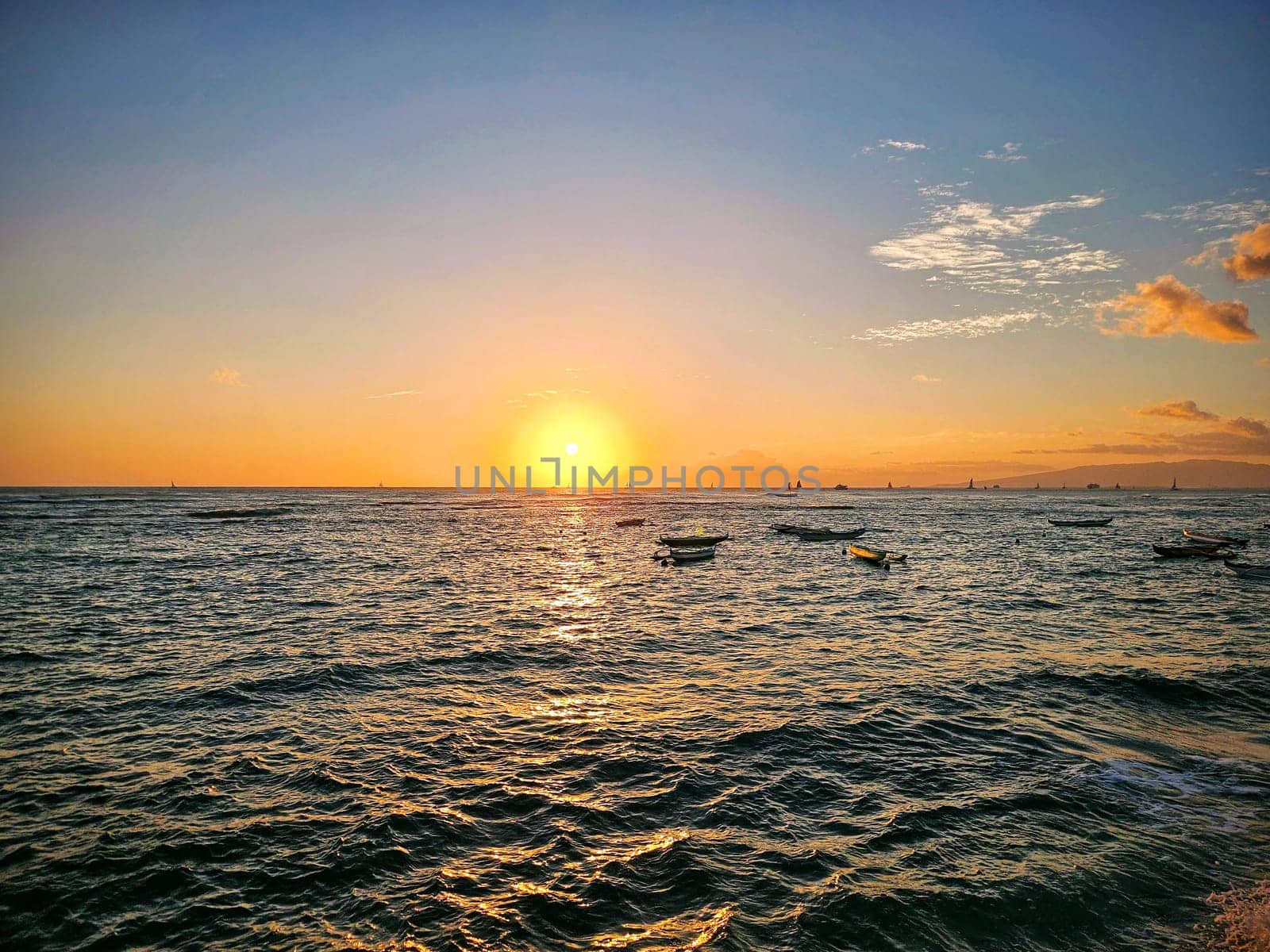 Sunset over the ocean reflecting on the water with boats park in ocean on Oahu, Hawaii.