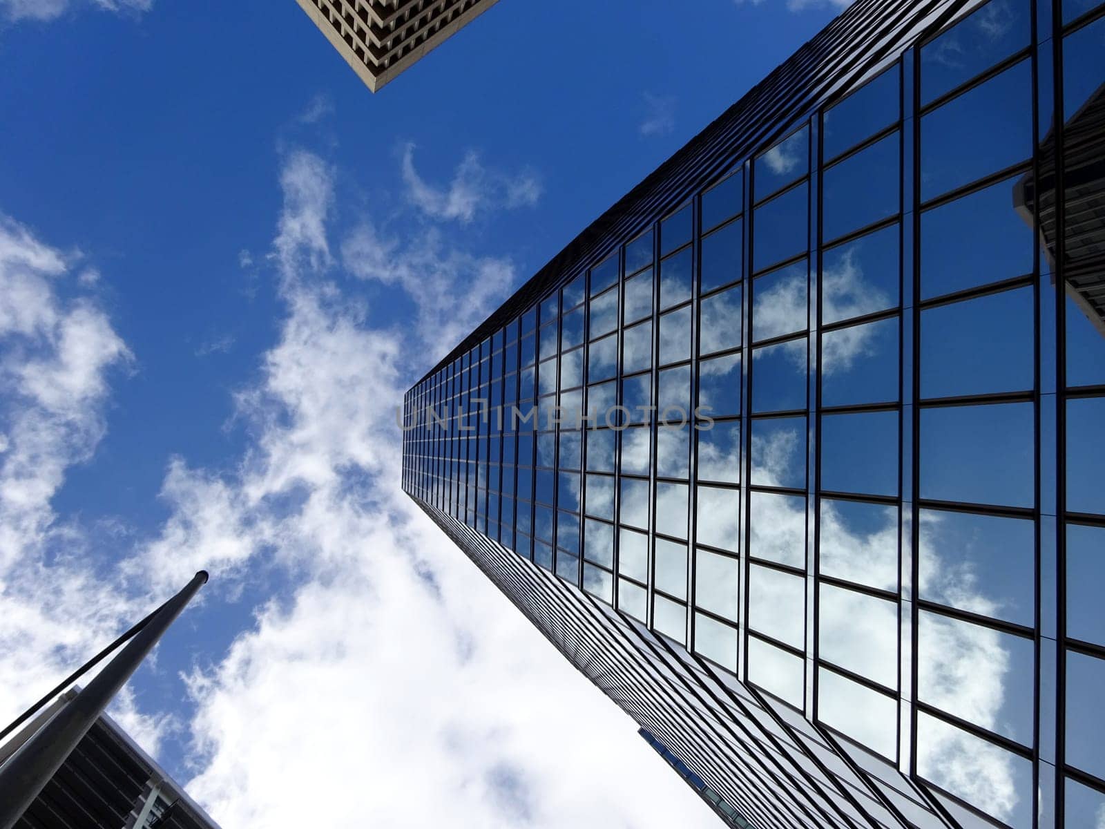 Honolulu - December 29, 2014: Glass building in downtown Honolulu, Hawaii. The building is reflecting the blue sky and white clouds. The photo is taken from a low angle, looking up at the building. The building is surrounded by other tall buildings. The photo shows the modern and urban architecture of Honolulu.