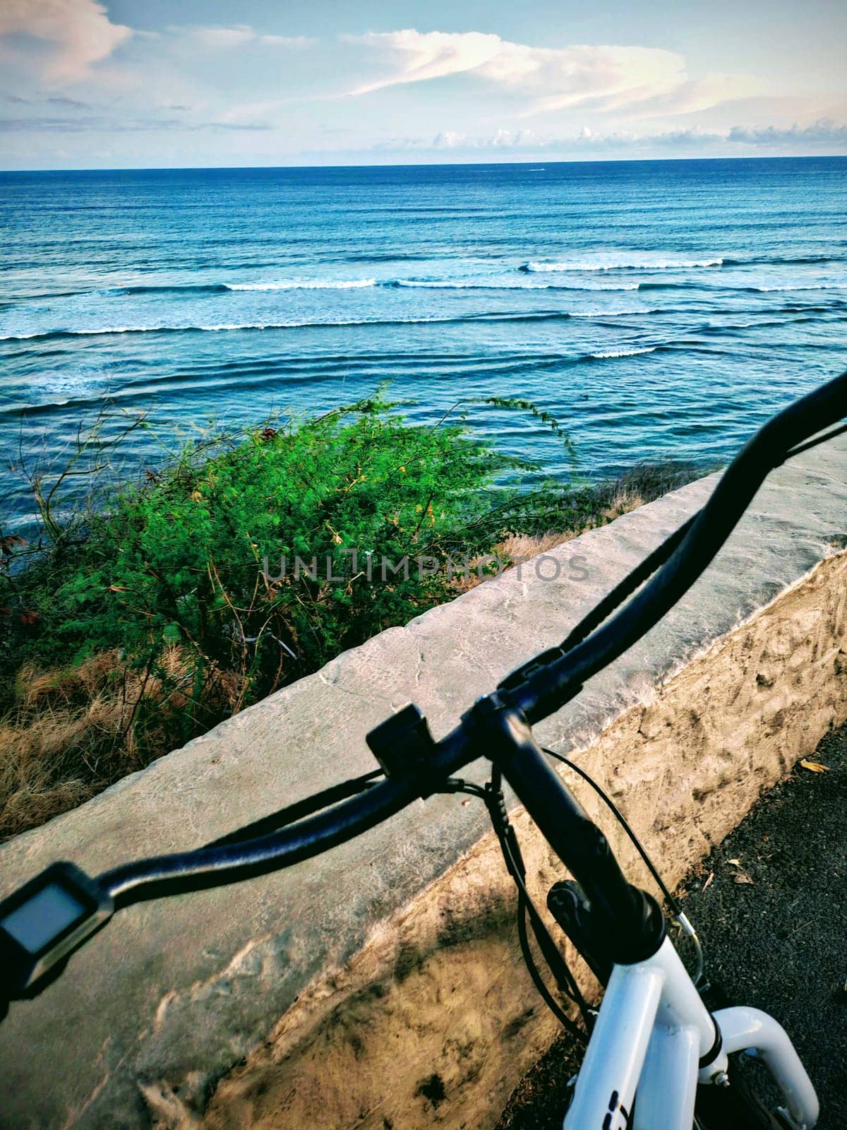 Honolulu - September 4, 2023: An ebike parked at the Diamond Head lookout with a beautiful view of the ocean. The photo shows the white bike with black handlebars and the blue water and sky in the background. The photo is taken from the perspective of someone standing behind the bike.
Keywords: 