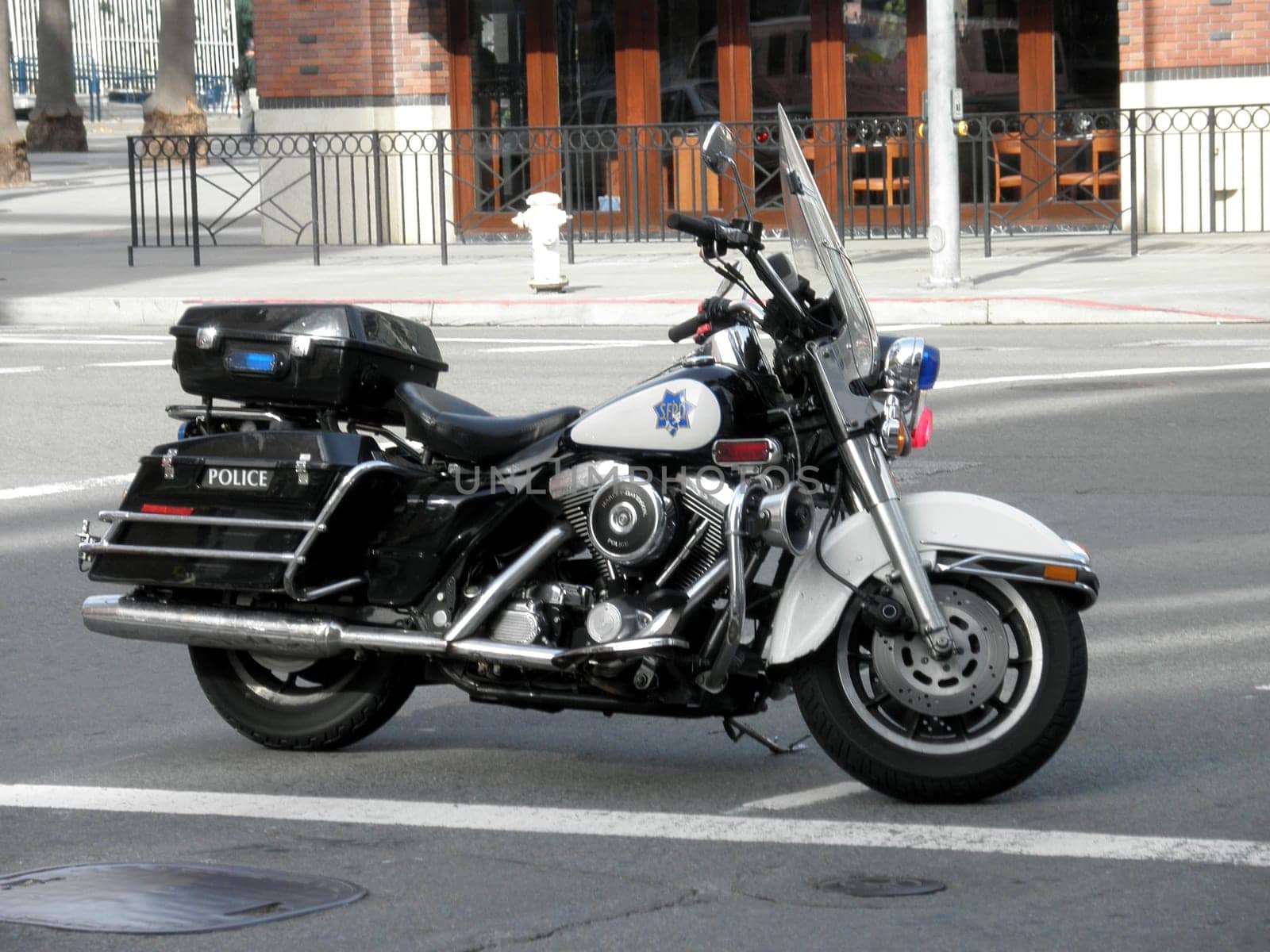 San Francisco - November 9, 2009:  San Francisco Police Department motorcycle parked on a city street. The motorcycle is black and white with a blue and white emblem on the side. The photo shows the details and features of the motorcycle, such as the windshield, the light, and the handle. The photo is taken from a close-up angle, focusing on the motorcycle.