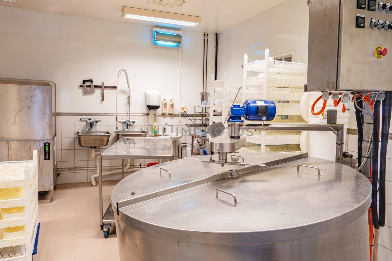 Interior view of a small cheese factory featuring specialized machinery and tools for the production of artisanal cheeses, with a rustic and inviting ambiance.