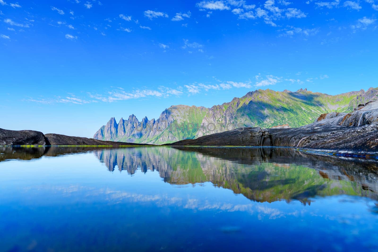A breathtaking image of a Norwegian summer day, capturing the fairytale landscape with its serene sea, majestic mountains, and stunning reflections in the sky.