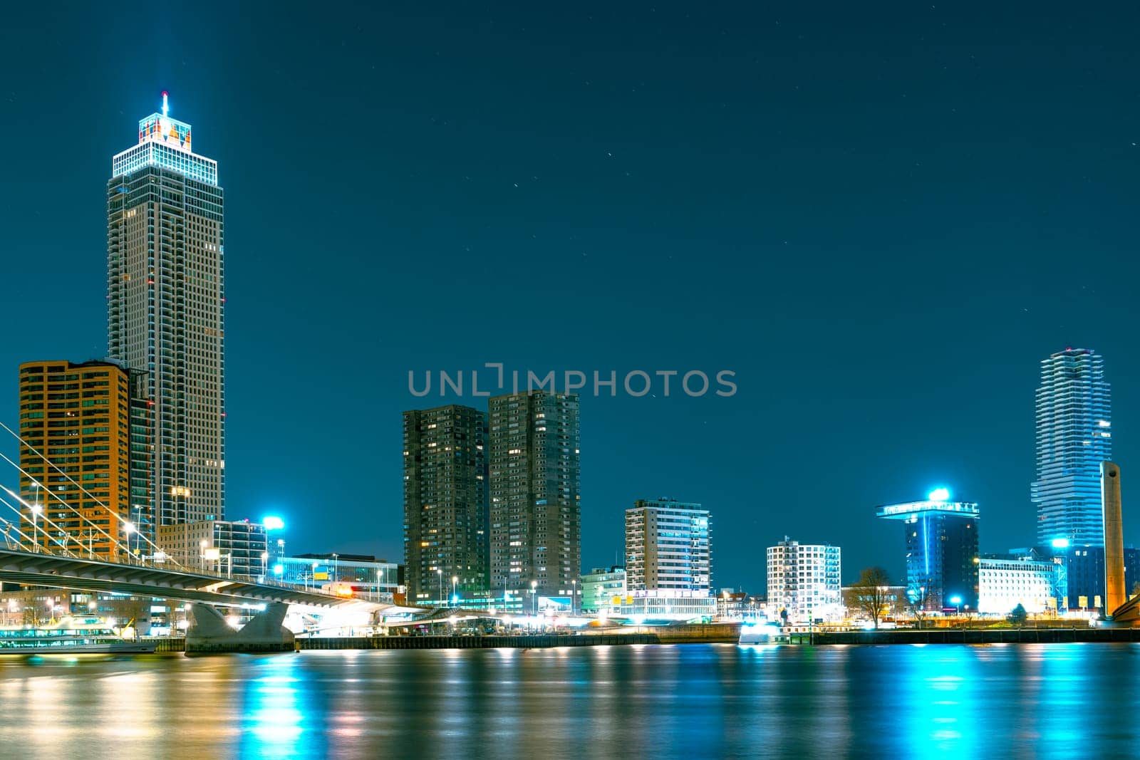 A stunning night panorama of Rotterdam featuring modern high-rise structures illuminated against a starry sky, creating a mesmerizing urban landscape.