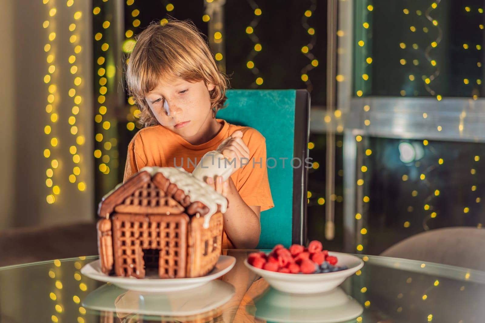 Immerse in festive delight as a boy crafts boy crafting an unconventional gingerbread house, infusing Christmas with unique creativity and festive cheer. A sweet scene of seasonal bonding and culinary fun.