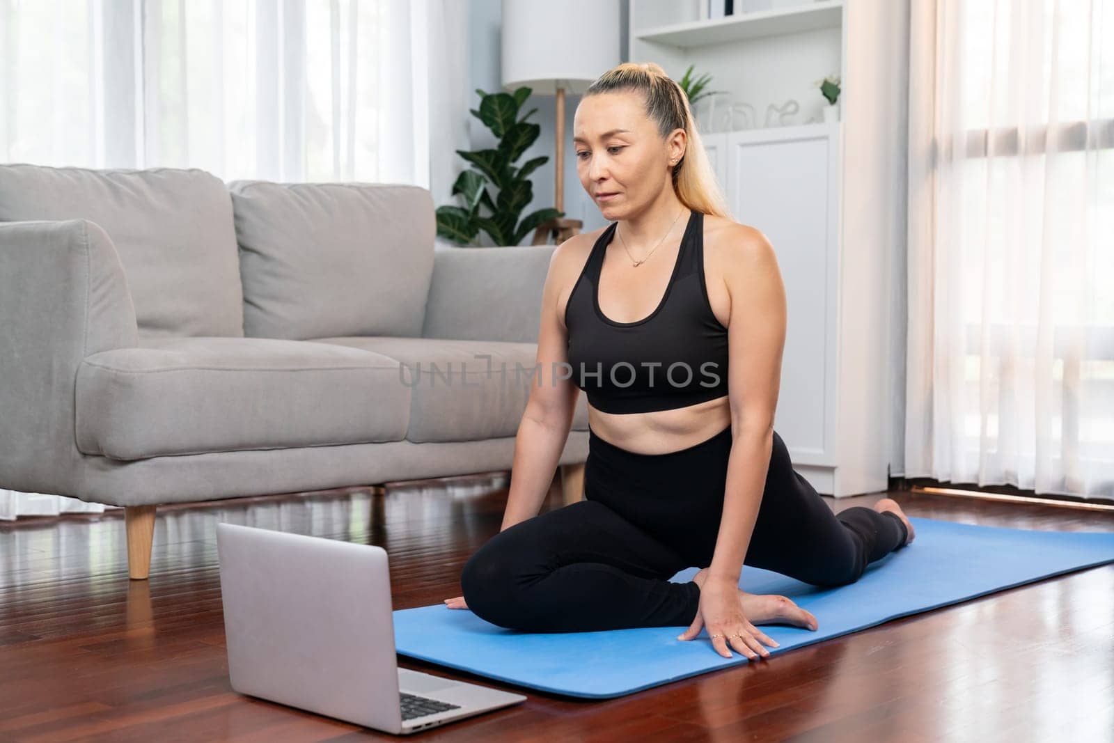 Senior woman in sportswear being doing yoga in meditation posture on exercising mat at home. Healthy senior pensioner lifestyle with peaceful mind and serenity. Clout