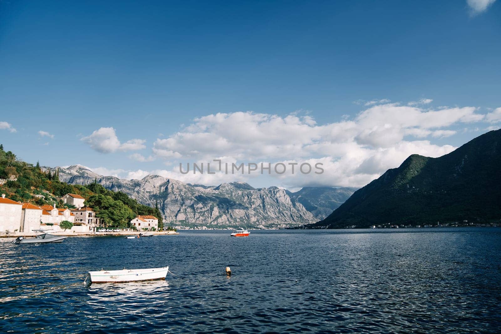 White fishing boat is moored in the sea off the coast of Perast. Montenegro by Nadtochiy