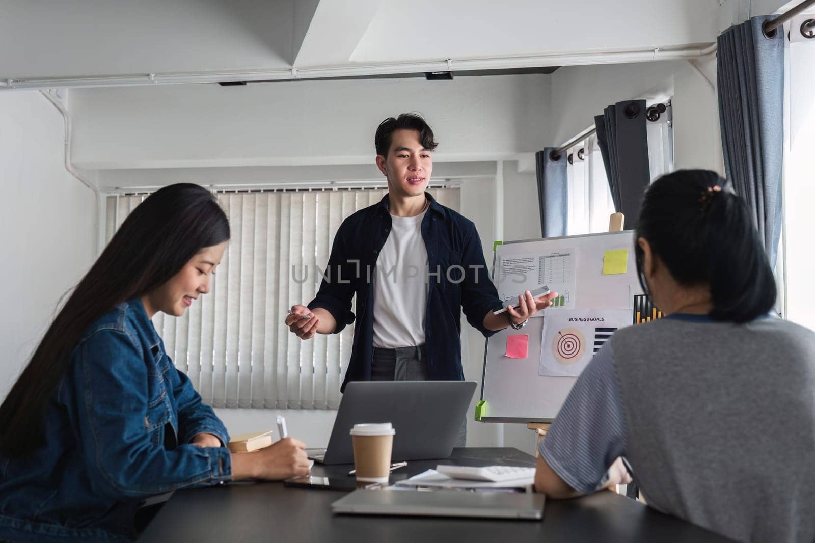 A professional business team is meeting to discuss company management practices in a modern conference room. by wichayada