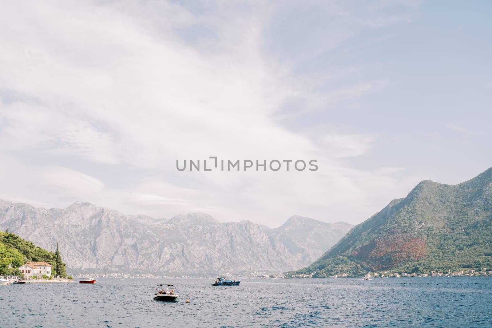 Motorboats sail along the Bay of Kotor against the backdrop of green mountains. Montenegro. High quality photo
