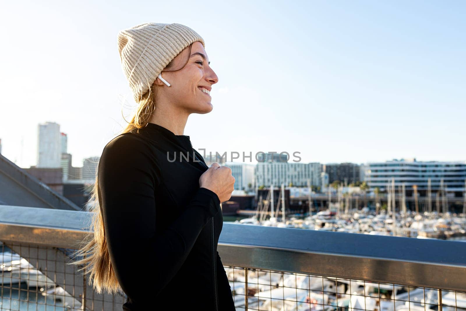 Happy young woman preparing to exercise outdoors during winter cold weather season. by Hoverstock