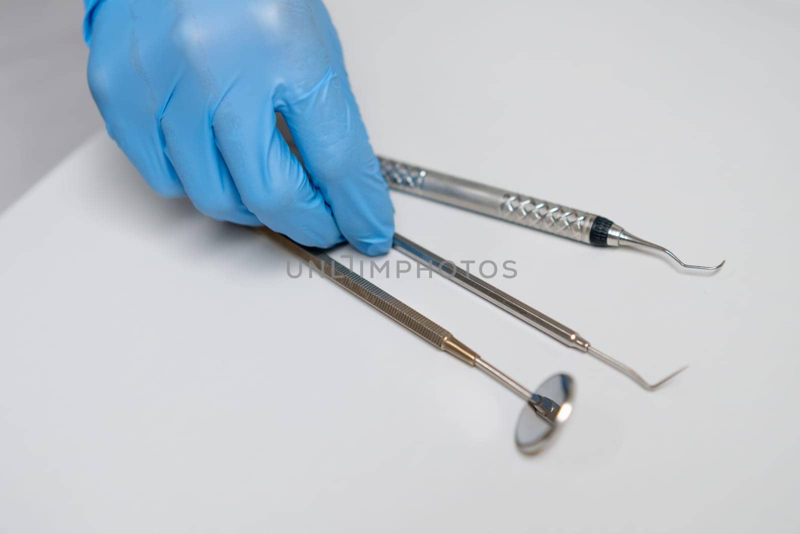 Close up dentist hand takes dental hook from the table.