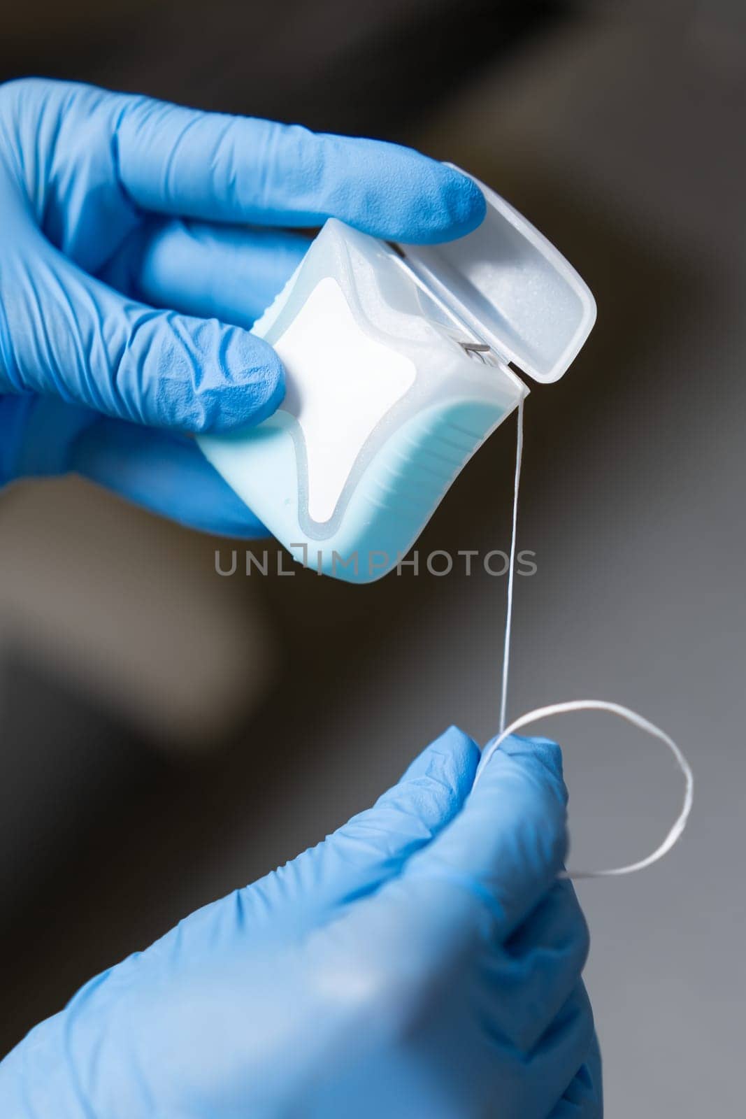Dental floss in the hands of a dentist clad in latex gloves. by vladimka