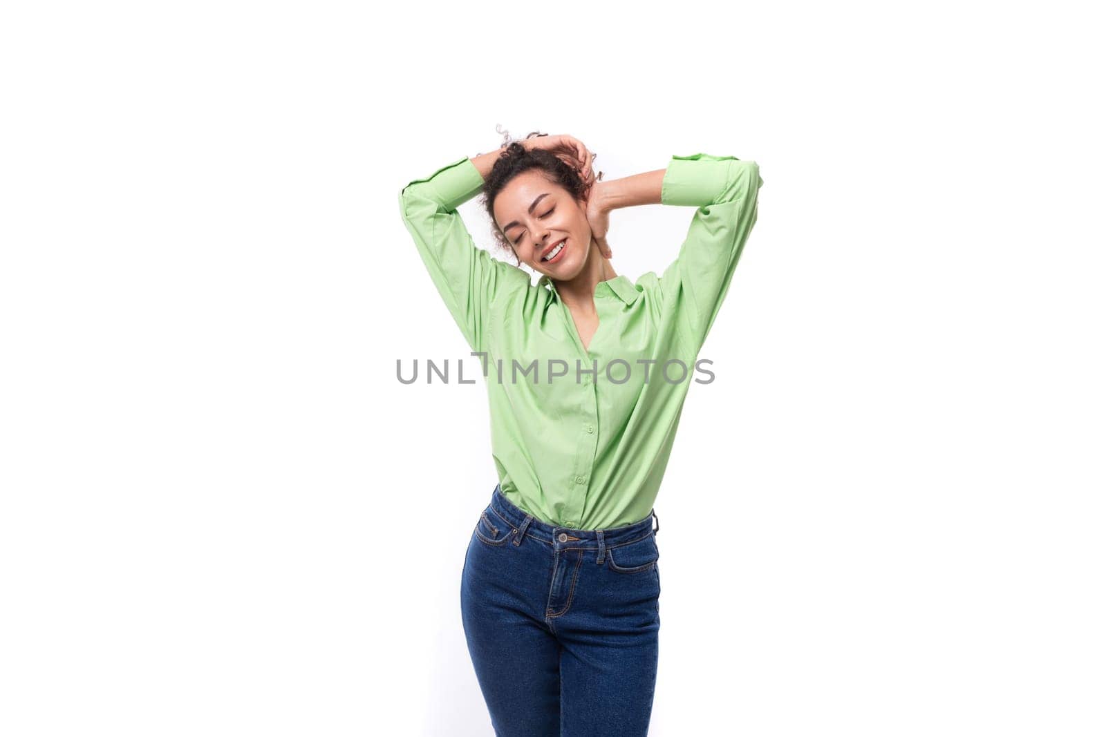 charming young brunette curly woman dressed in a green shirt and jeans by TRMK