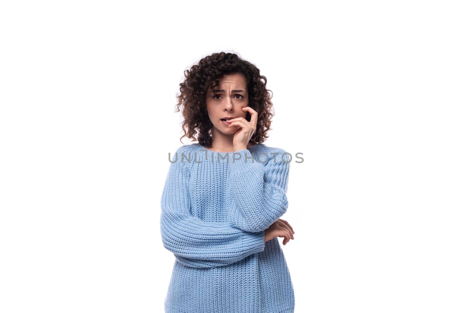 pretty young curly brunette woman dressed in a blue sweater on a white background by TRMK