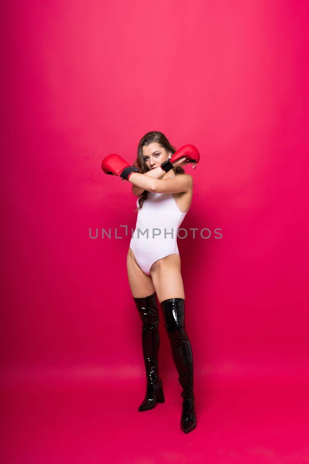 Studio portrait of female seductive boxer in bodysuit and gloves