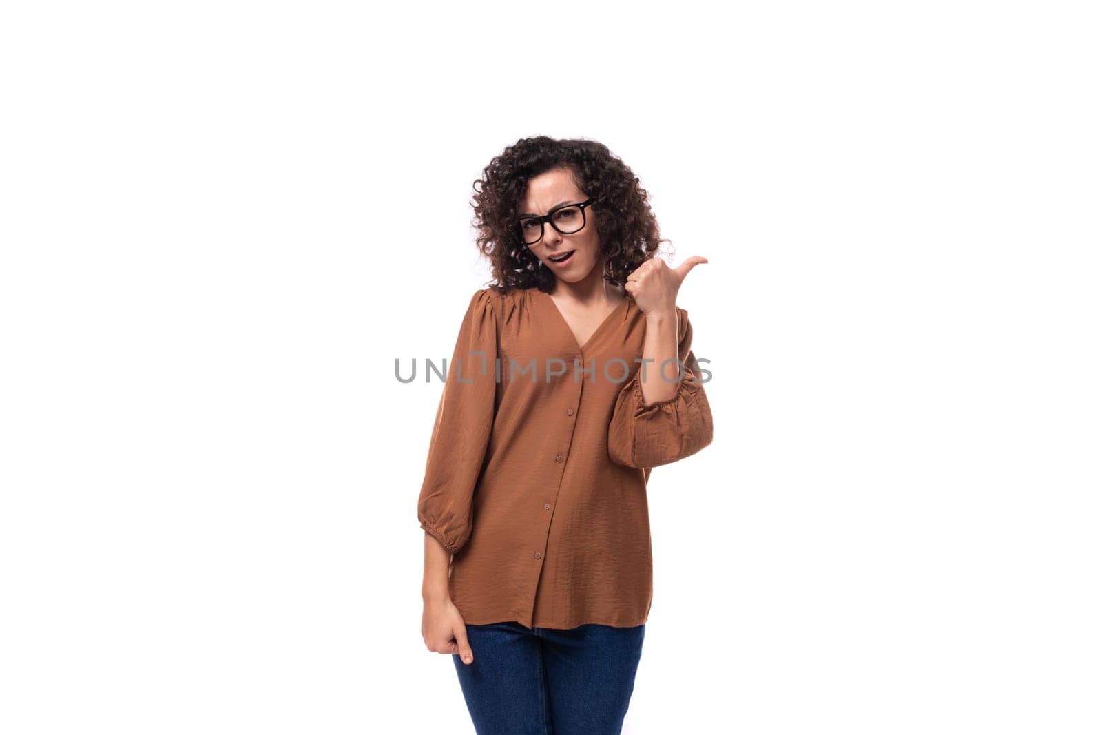 portrait of a young stylish slim brunette woman with curly hair dressed in a brown shirt.