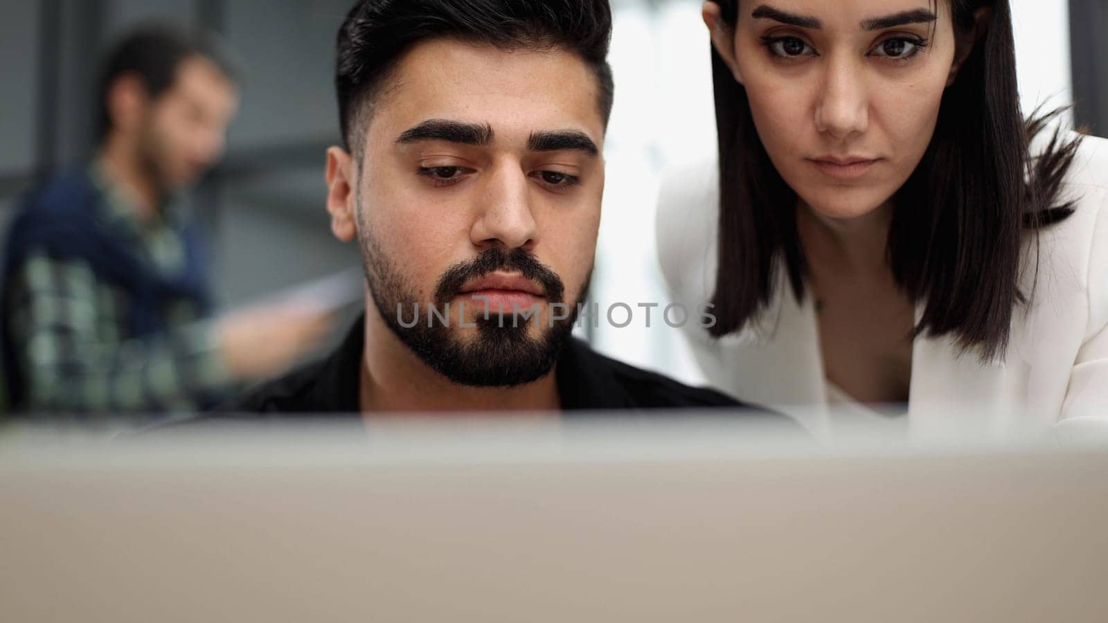 Seriously focused determined young bearded businessman or freelancer sitting at the table,