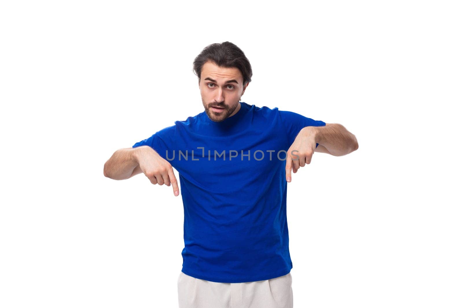 a young brutal European brunette man with a beard dressed in a blue T-shirt gesticulates with his hands.
