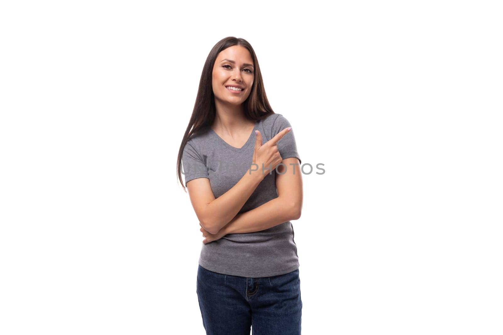 young well-groomed caucasian woman with dark straight hair is dressed in a casual gray t-shirt on a studio background with copy space.