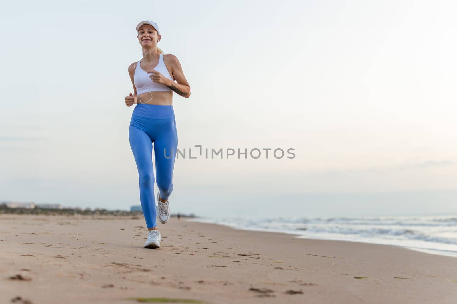 Beautiful sportive woman running along beautiful sandy beach, healthy lifestyle, enjoying active summer vacation near the sea. High quality photo