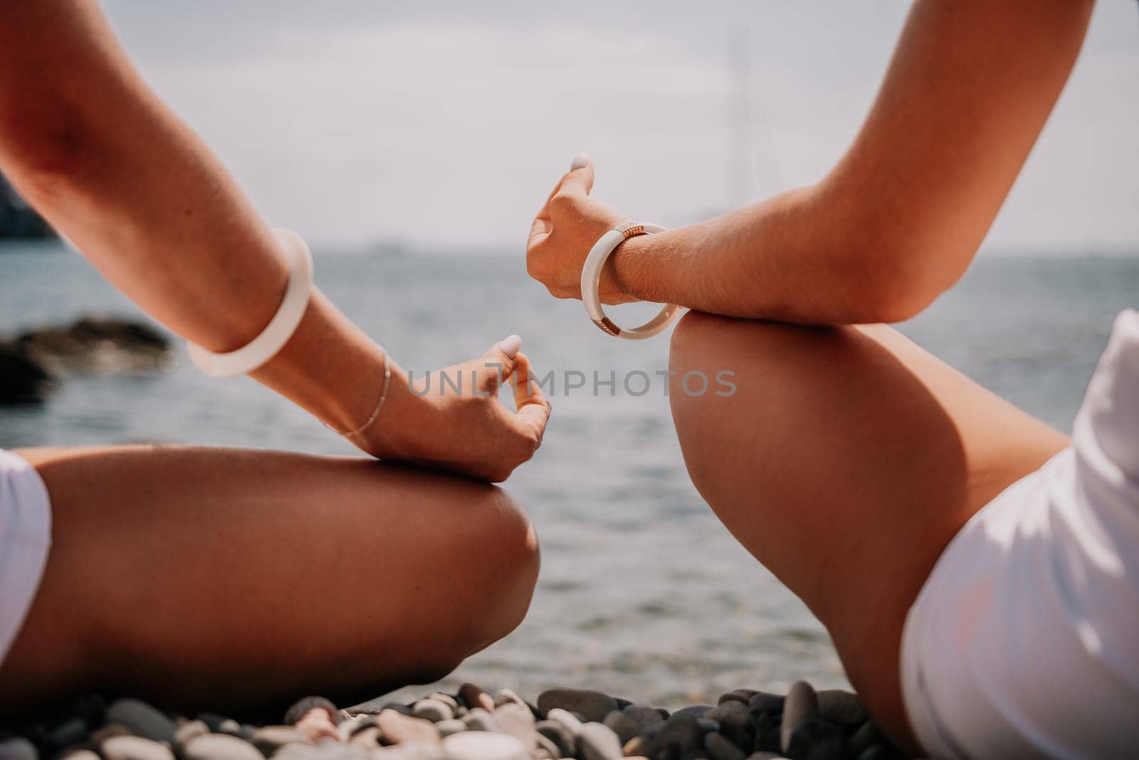 Woman sea yoga. Happy women meditating in yoga pose on the beach, ocean and rock mountains. Motivation and inspirational fit and exercising. Healthy lifestyle outdoors in nature, fitness concept. by panophotograph