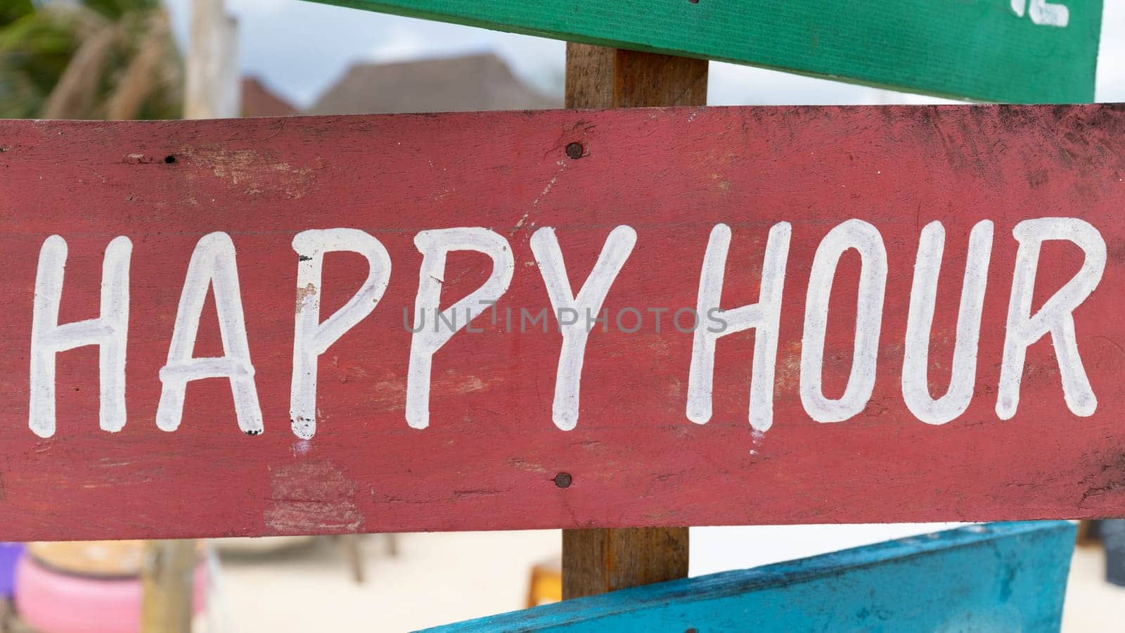 Red sign with white writing "Happy hour" on sandy beach at sunny day,relax and summer concept.