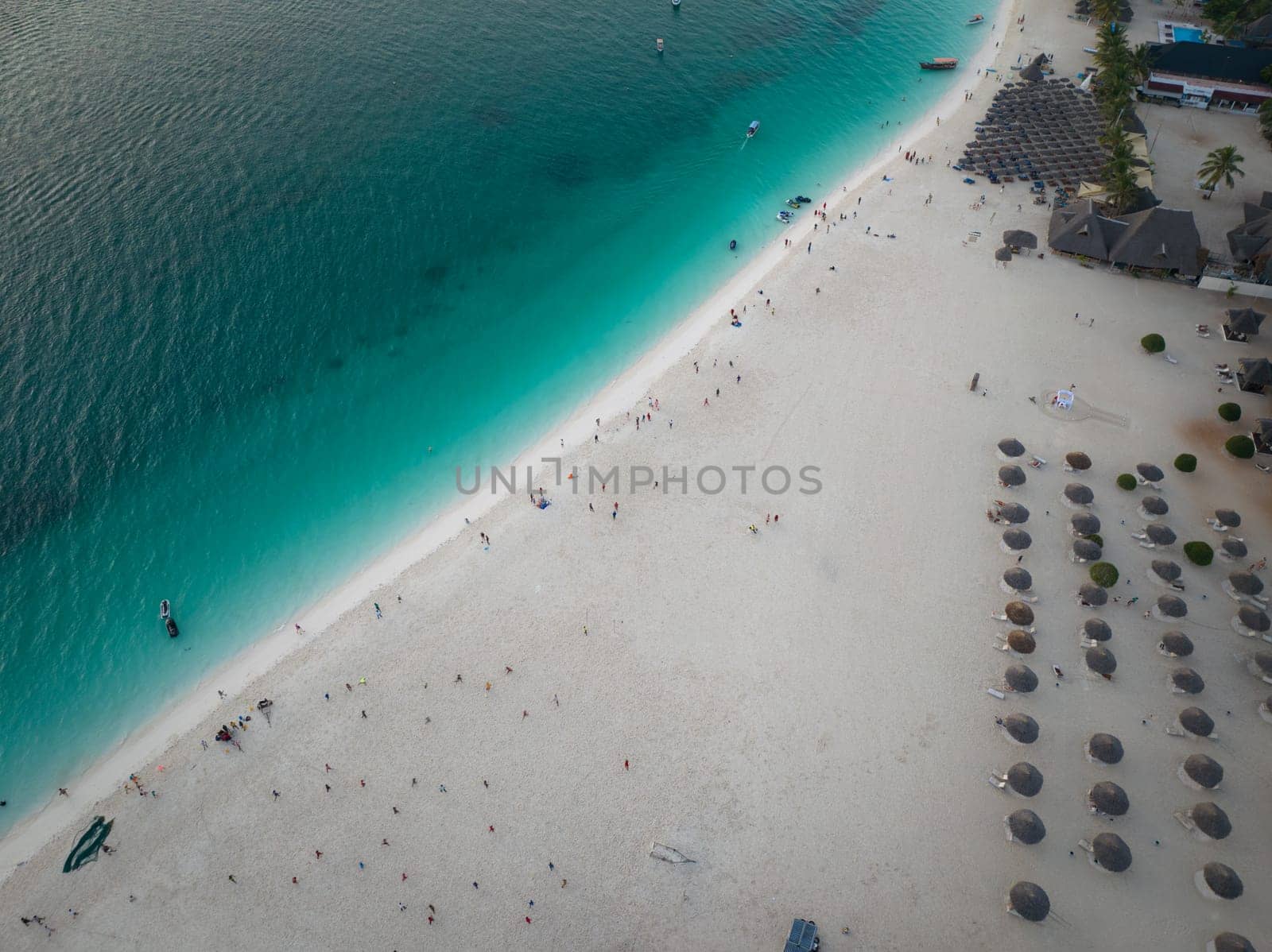 Birds view of green ocean and wonderful white sandy beach with people, copy space, Zanzibar in Tanzania.