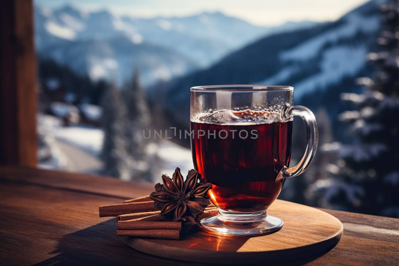 A glass of hot mulled wine with spices on a table overlooking the mountains.