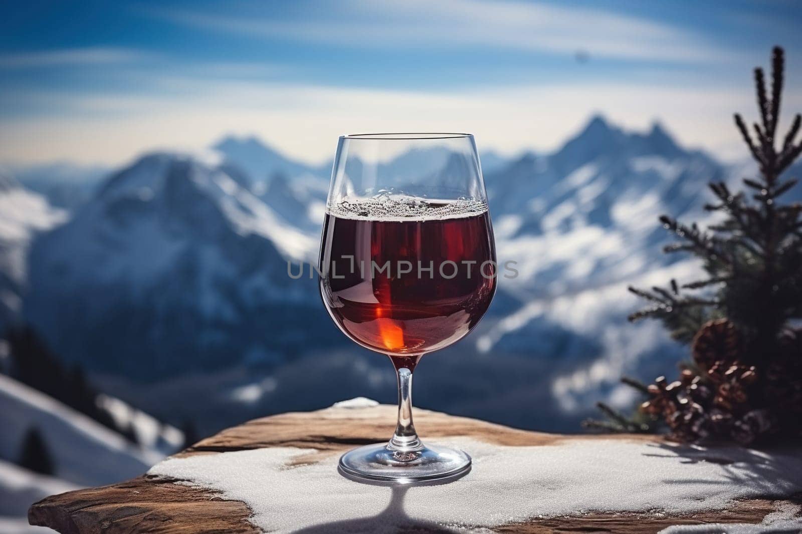 A glass of hot mulled wine with spices on a table overlooking the mountains.