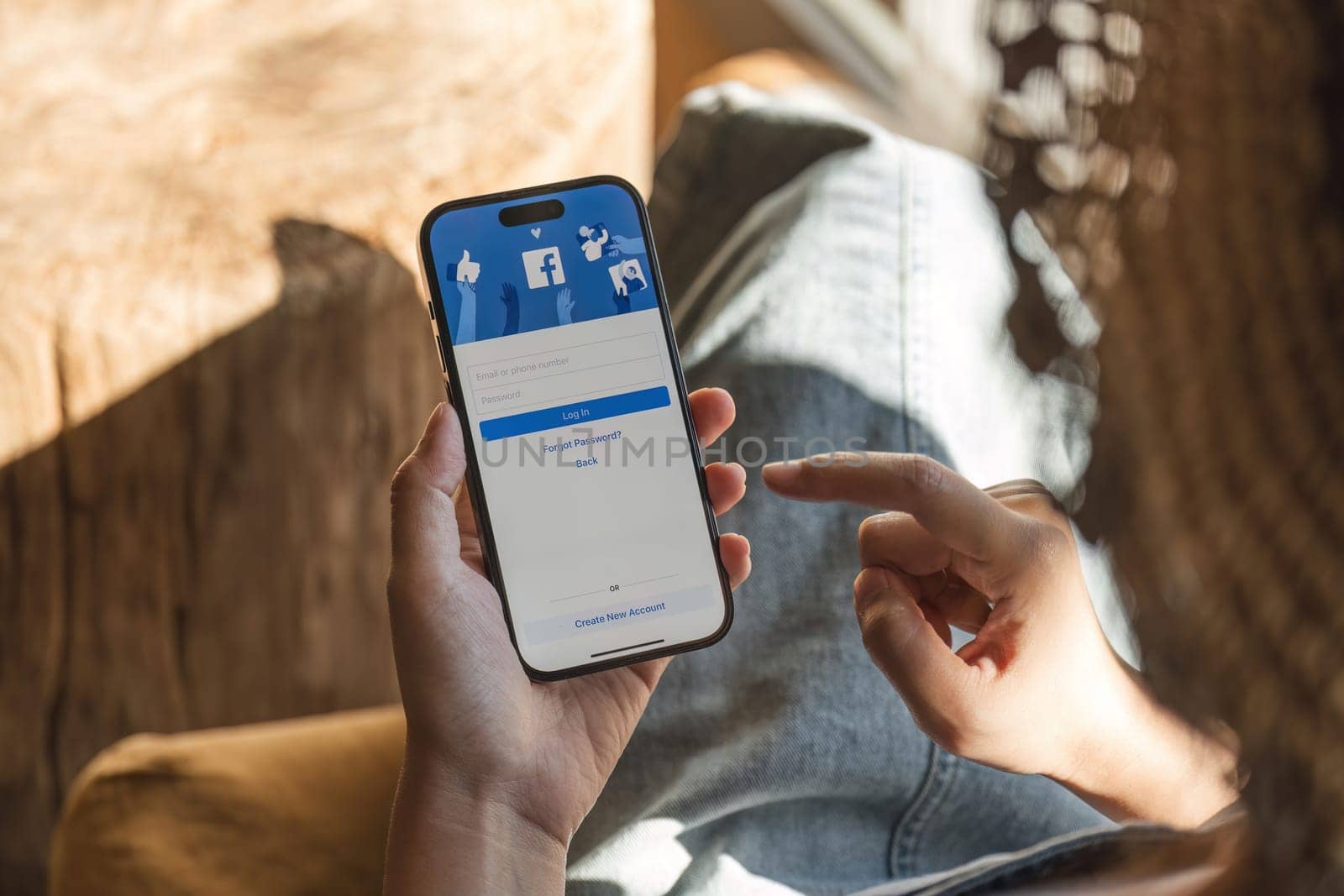 CHIANG MAI ,THAILAND - DEC 5, 2023 : Woman hand holding iPhone 14 to use facebook with new login screen.Facebook is a largest social network and most popular social networking site in the world..