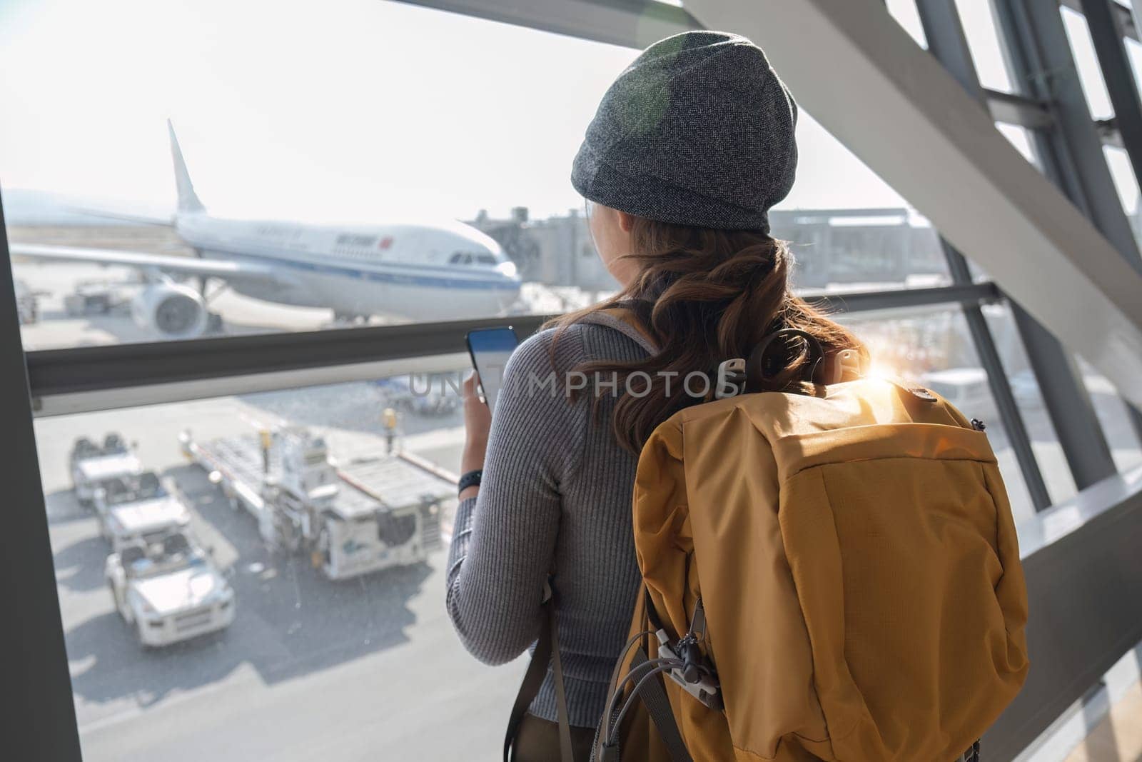 Portrait Back of a young Asian woman checking flight times in the airport to travel on vacation. by wichayada