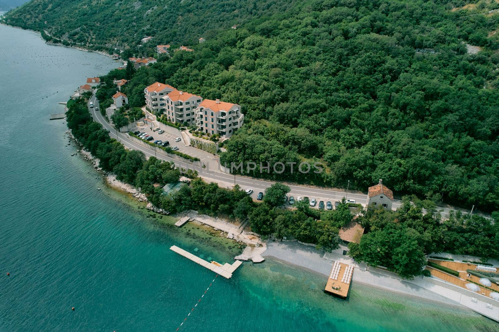 Multi-storey hotels with a private pier at the foot of green mountains on the seashore. Drone. High quality photo