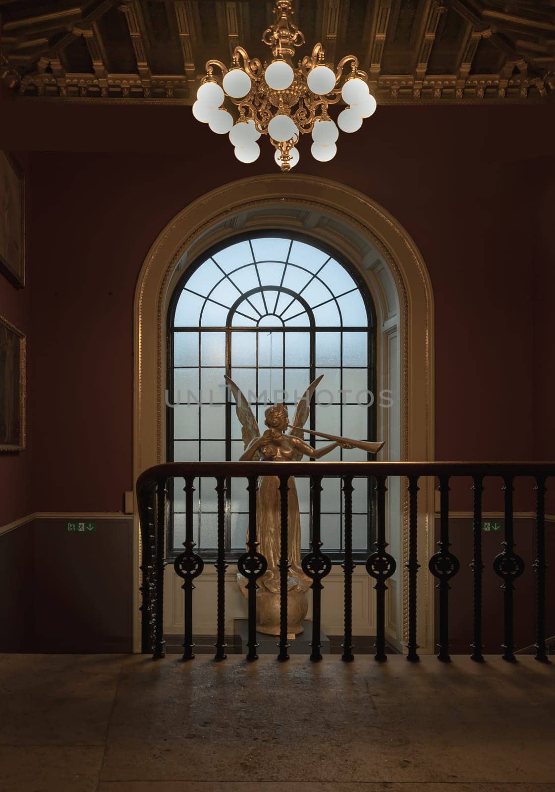 London, UK - Nov 27, 2023 - View of Angel statue in front of wooden window on red wall at the Victoria and Albert Museum. Abstract interior design, Space for text, Selective focus.
