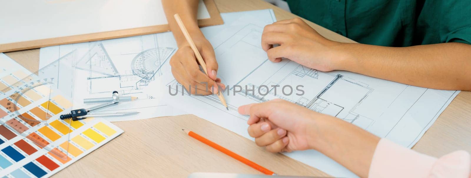 Professional architect drafts blueprint from project manager advice on table with house model, color palette and architectural equipment. Creative design concept. Focus on hand. Closeup. Variegated.