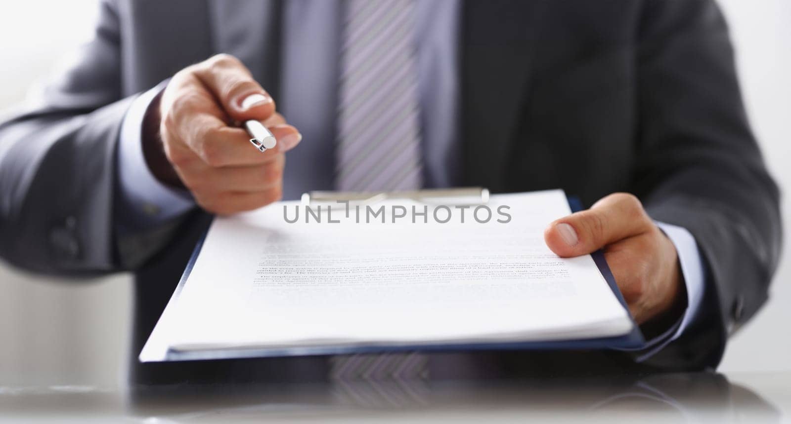 Male arm in suit offer contract form on clipboard pad and silver pen to sign closeup. Strike a bargain for profit, white collar motivation union decision corporate sale insurance agent concept